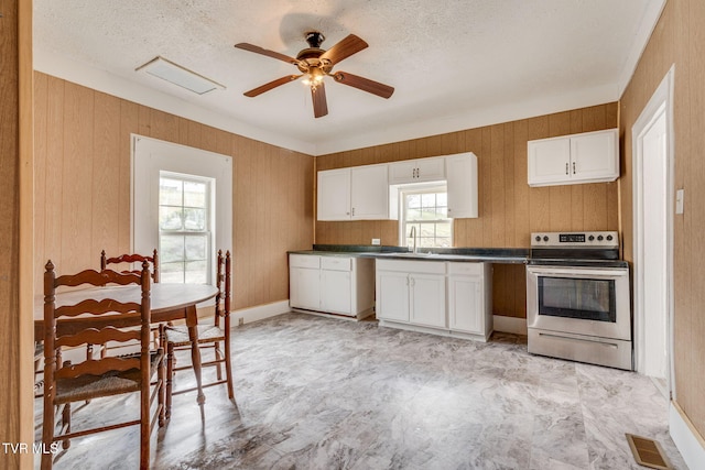 kitchen with a healthy amount of sunlight, a sink, dark countertops, and stainless steel range with electric stovetop