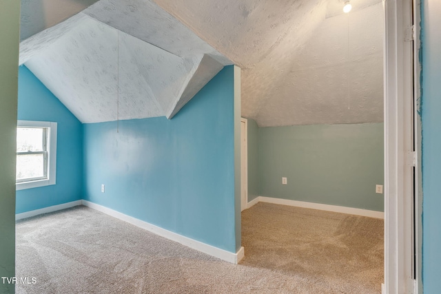 additional living space with baseboards, carpet flooring, lofted ceiling, and a textured ceiling