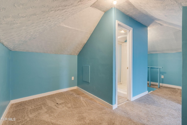additional living space featuring a textured ceiling, baseboards, vaulted ceiling, and carpet
