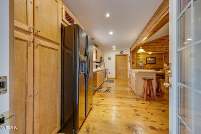 kitchen with light wood finished floors, stainless steel microwave, recessed lighting, black refrigerator with ice dispenser, and light countertops