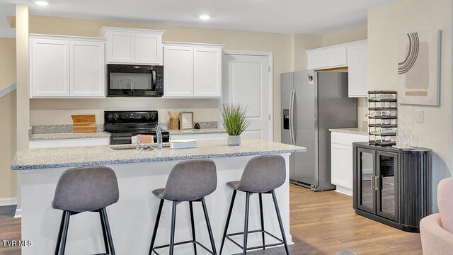 1905 Fox Meadows Cir, Bluff City, TN 37618 - kitchen with black appliances, white cabinetry, a kitchen island with sink, a kitchen bar, and recessed lighting