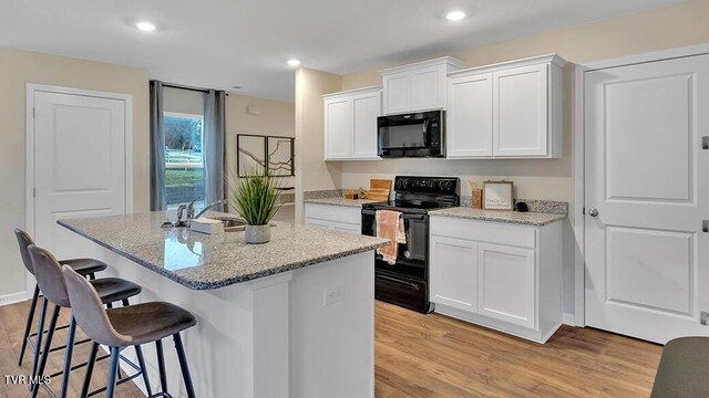 1905 Fox Meadows Cir, Bluff City, TN 37618 - kitchen featuring black appliances, a breakfast bar area, light wood-style floors, an island with sink, and recessed lighting