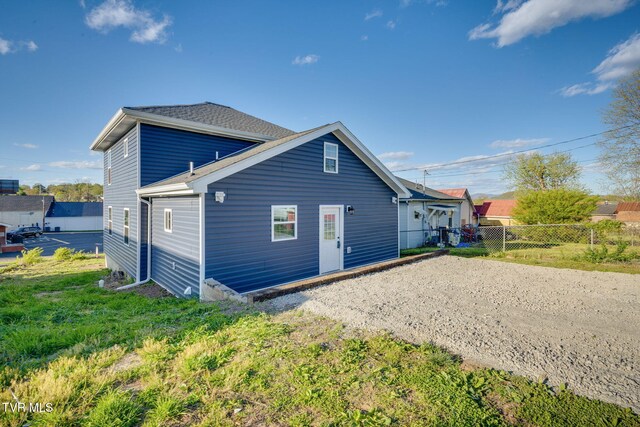 rear view of property with fence and dirt driveway