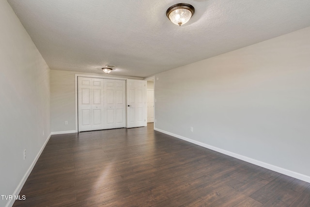 unfurnished bedroom with baseboards, dark wood-type flooring, a textured ceiling, and a closet
