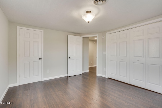 unfurnished bedroom with dark wood-style floors, baseboards, and a closet