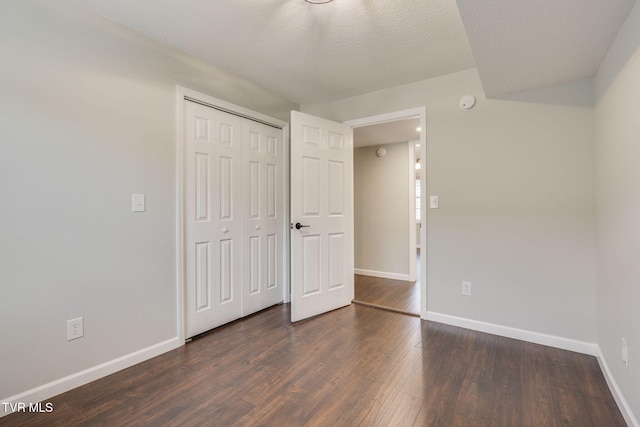 unfurnished bedroom with baseboards, wood finished floors, a closet, and a textured ceiling