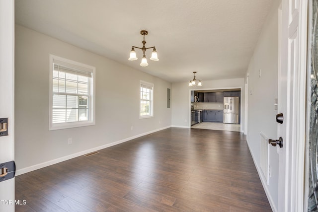 unfurnished living room featuring a chandelier, electric panel, dark wood-style floors, and baseboards