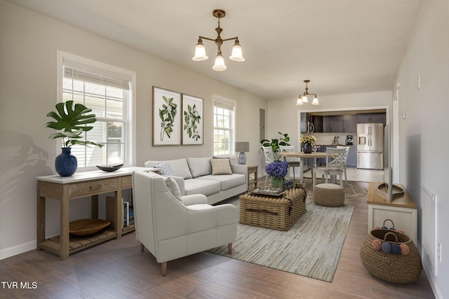 living area featuring a chandelier, wood finished floors, and baseboards