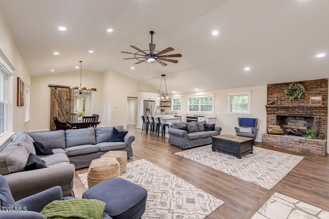 368 New Hope Rd, Jonesborough, TN 37659 - living room featuring a chandelier, vaulted ceiling, light wood-style flooring, a barn door, and a fireplace