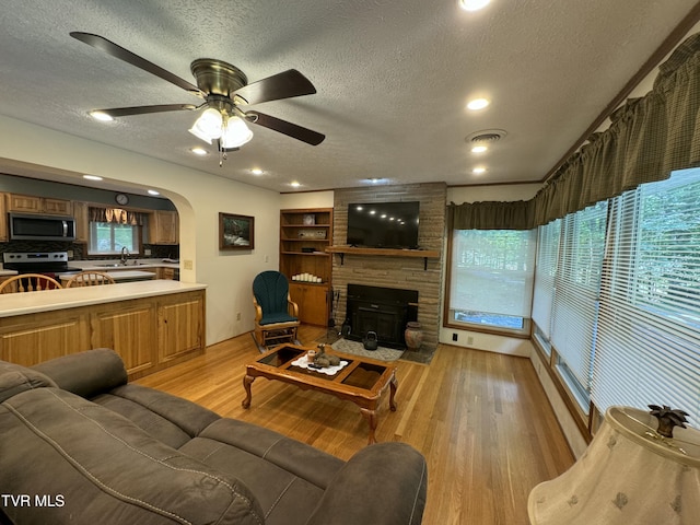 living area featuring arched walkways, light wood-style flooring, a textured ceiling, and visible vents