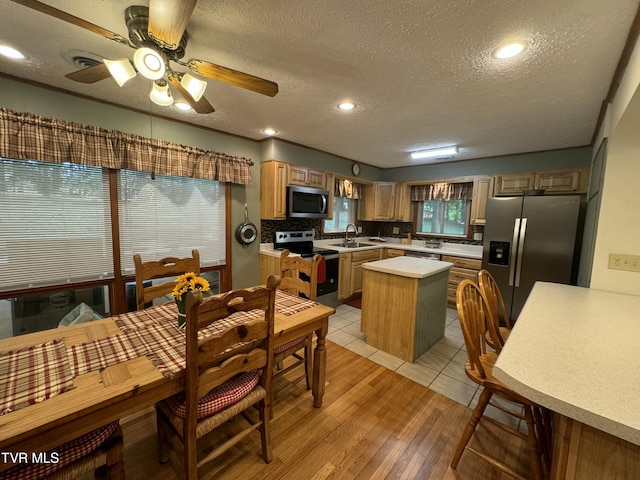 kitchen with light countertops, a textured ceiling, backsplash, and appliances with stainless steel finishes