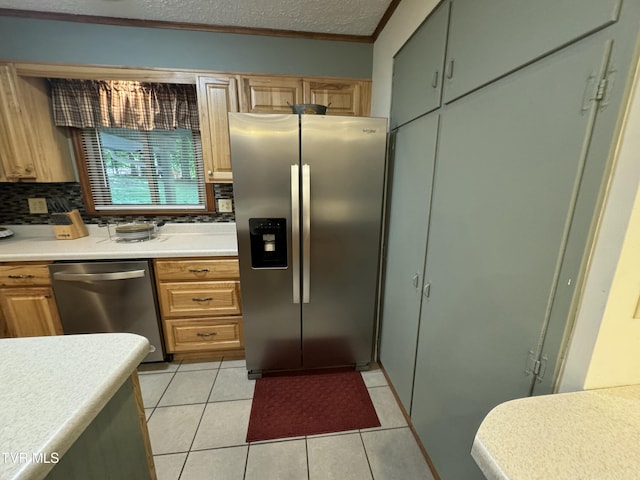 kitchen with stainless steel appliances, light countertops, ornamental molding, light tile patterned floors, and decorative backsplash