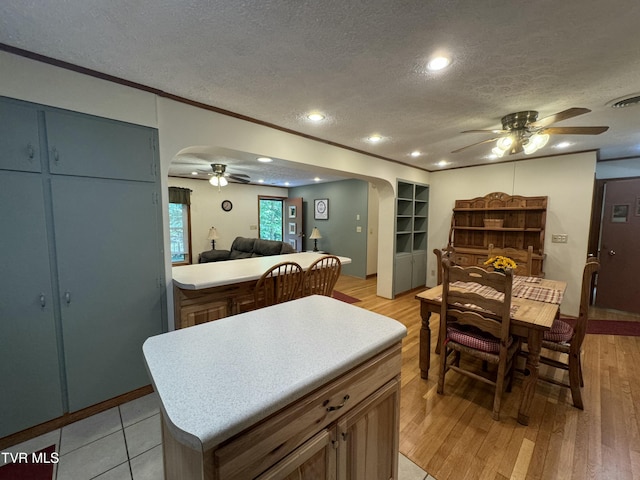 interior space with light wood finished floors, arched walkways, a textured ceiling, and ceiling fan