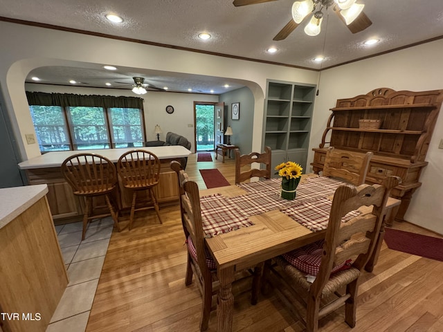 dining space featuring arched walkways, crown molding, and a ceiling fan