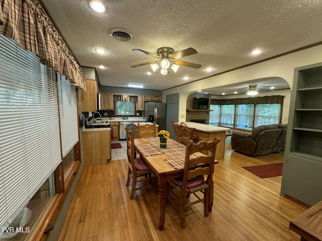 dining space featuring arched walkways, a textured ceiling, visible vents, and a ceiling fan