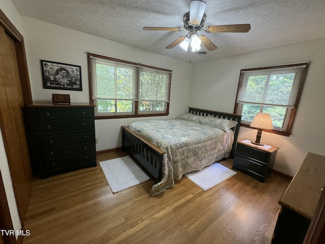 bedroom with baseboards, wood finished floors, a textured ceiling, and ceiling fan