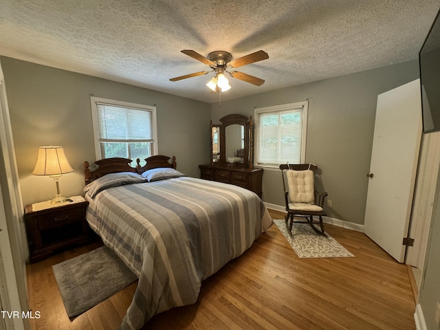bedroom with light wood-style flooring, a textured ceiling, and multiple windows
