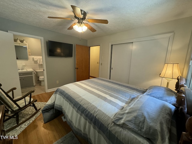 bedroom featuring wood finished floors, a ceiling fan, a closet, a textured ceiling, and ensuite bathroom