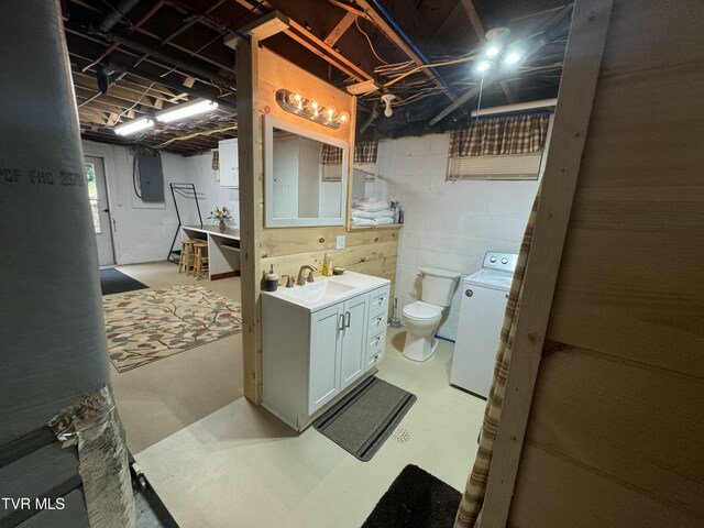 bathroom featuring electric panel, toilet, concrete floors, vanity, and washer / dryer
