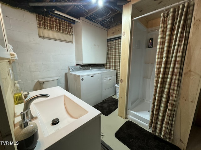 bathroom featuring concrete block wall, vanity, washer and dryer, and a shower stall