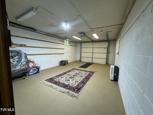 garage featuring concrete block wall and a garage door opener