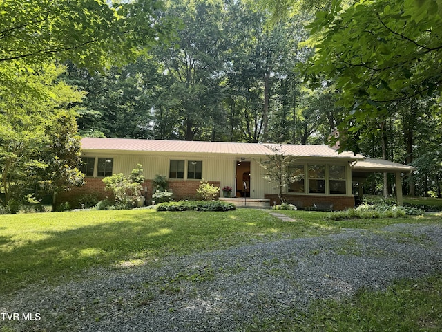 single story home featuring brick siding, driveway, a front lawn, and metal roof