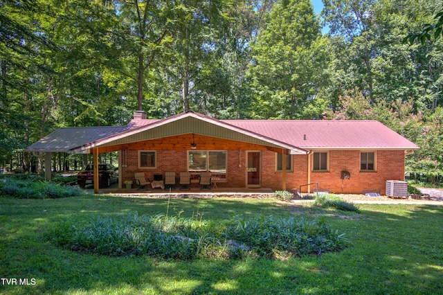 rear view of property featuring central AC, brick siding, a yard, and a patio