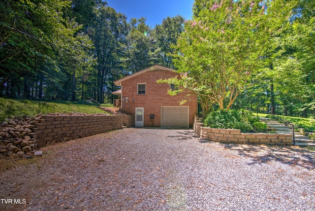 view of side of property with brick siding, driveway, and a garage
