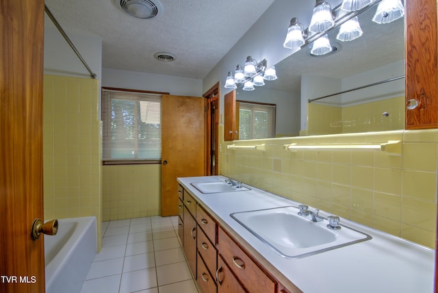 full bath with a textured ceiling, a sink, tile walls, tile patterned flooring, and visible vents