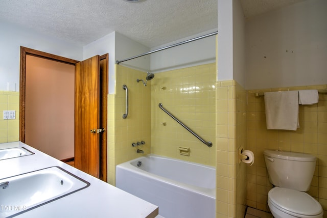 bathroom featuring a wainscoted wall, toilet, tile walls, shower / bathing tub combination, and a textured ceiling