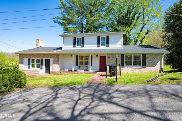 view of front of property with a porch, a front lawn, a chimney, and brick siding