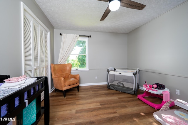 bedroom featuring a ceiling fan, wood finished floors, a textured ceiling, a closet, and baseboards