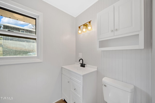 bathroom with toilet, ornamental molding, and vanity