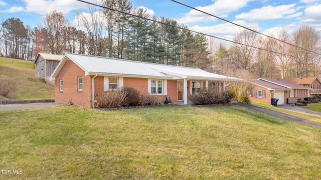 single story home with driveway, brick siding, and a front yard