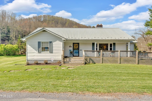 ranch-style home with a chimney, covered porch, a front yard, and metal roof