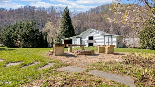 view of front of home with a front lawn, an outdoor structure, and a wooded view