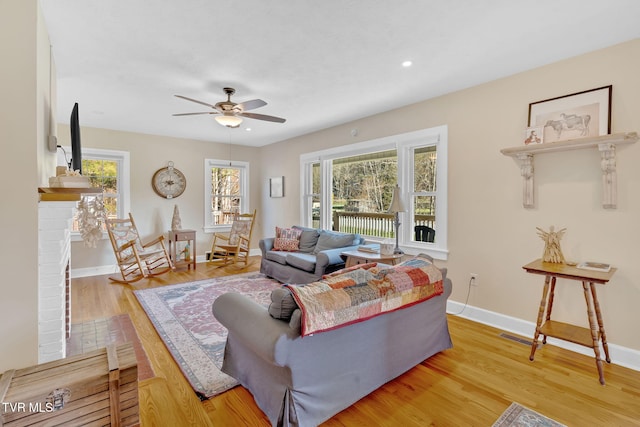 living room featuring light wood-type flooring, baseboards, recessed lighting, visible vents, and ceiling fan