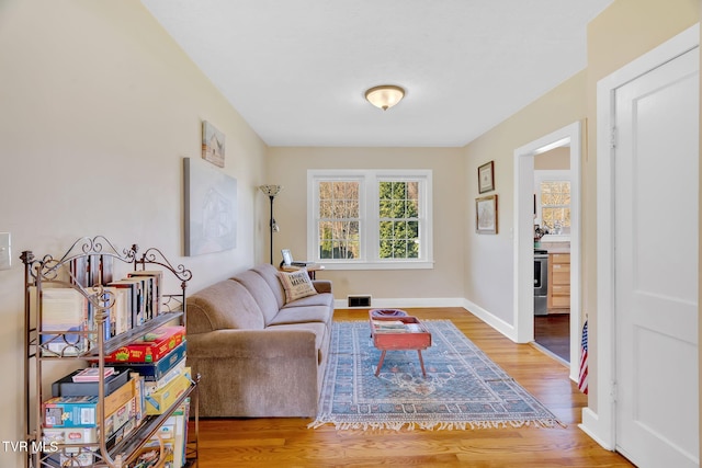 living area featuring visible vents, baseboards, and wood finished floors