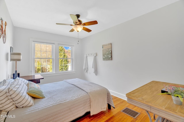 bedroom with baseboards, wood finished floors, visible vents, and ceiling fan