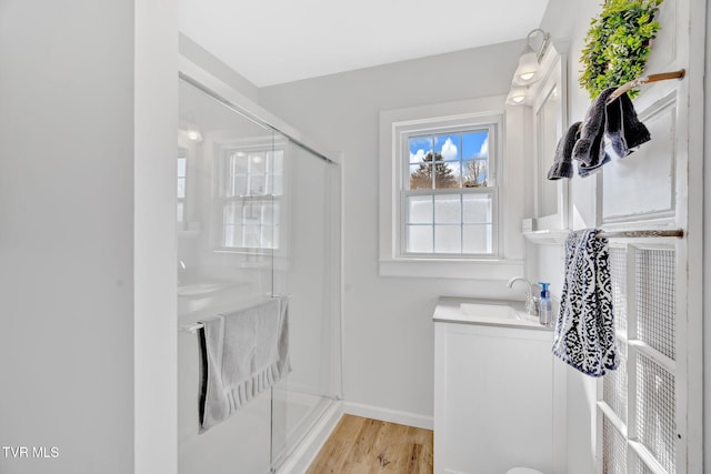 full bathroom with baseboards, wood finished floors, vanity, and a stall shower