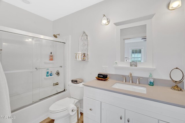 full bathroom featuring vanity, bath / shower combo with glass door, and toilet