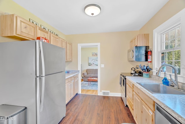 kitchen with light brown cabinetry, visible vents, a sink, dark wood-type flooring, and appliances with stainless steel finishes