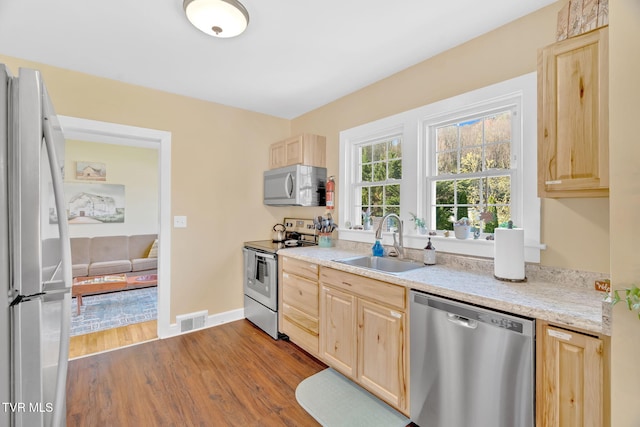 kitchen featuring light brown cabinets, stainless steel appliances, and a sink
