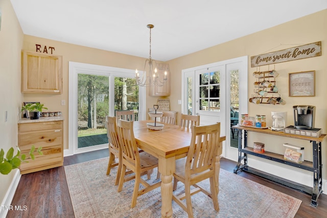 dining space featuring baseboards, a chandelier, and dark wood-style floors