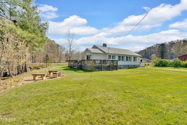 exterior space featuring a chimney, a deck with mountain view, and a yard