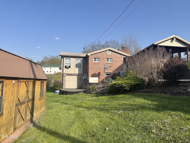 490 Delaney Ln, Clintwood, VA 24228 - rear view of property featuring a lawn, central air condition unit, a chimney, an attached garage, and brick siding
