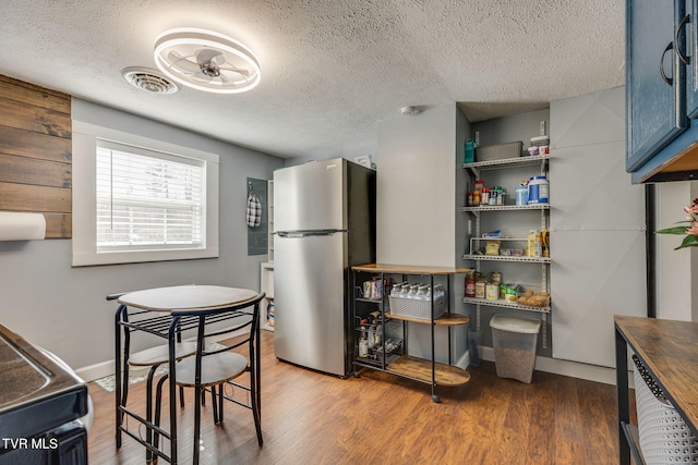 kitchen featuring wood finished floors, visible vents, blue cabinets, freestanding refrigerator, and butcher block countertops