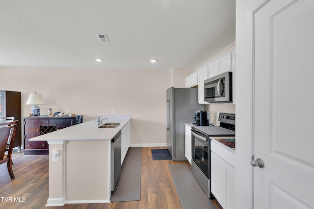 1245 Cherry Grv, Greeneville, TN 37745 - kitchen with stainless steel appliances, a peninsula, wood finished floors, a sink, and white cabinets