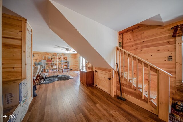 bonus room with wood finished floors, wood walls, and a ceiling fan