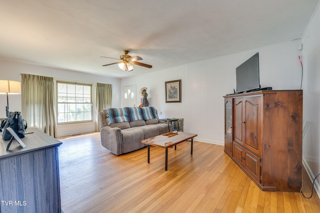 living area featuring ceiling fan, baseboards, and light wood-style flooring